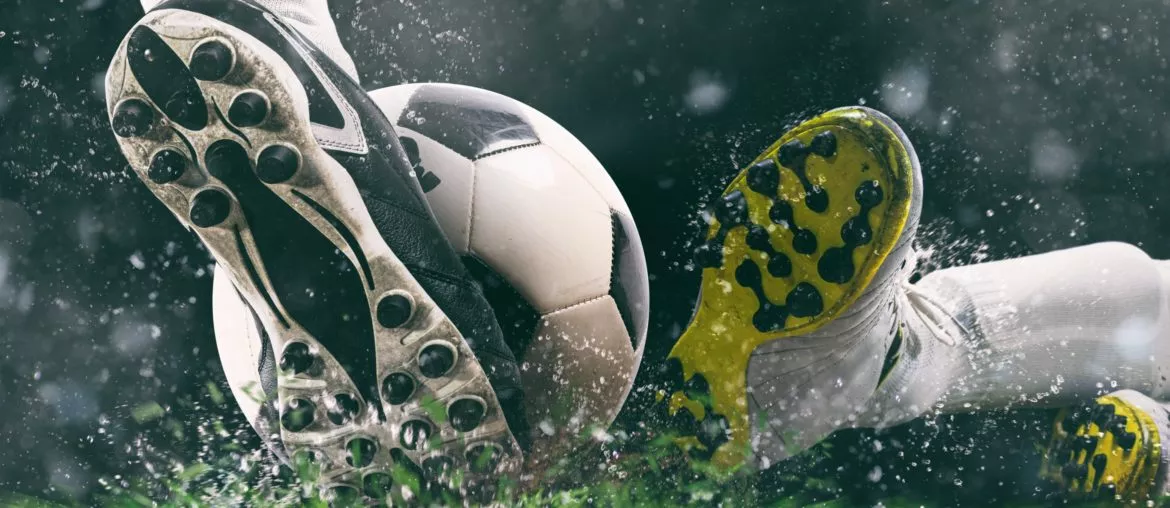 Sports washing - Football scene at night match with close up of a soccer shoe hitting the ball with power by alphaspirit