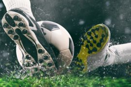 Sports washing - Football scene at night match with close up of a soccer shoe hitting the ball with power by alphaspirit